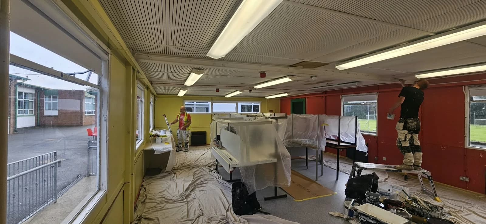 Tables and furniture covered in protective sheeting in a classroom being redecorated